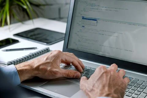 Programmer writing code on laptop computer in office. website programming, so Stockfoto's