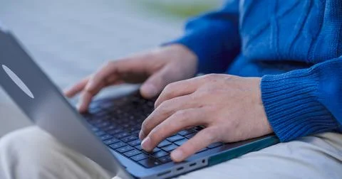 Programmer writing code on laptop keyboard, working remotely outdoors 写真素材