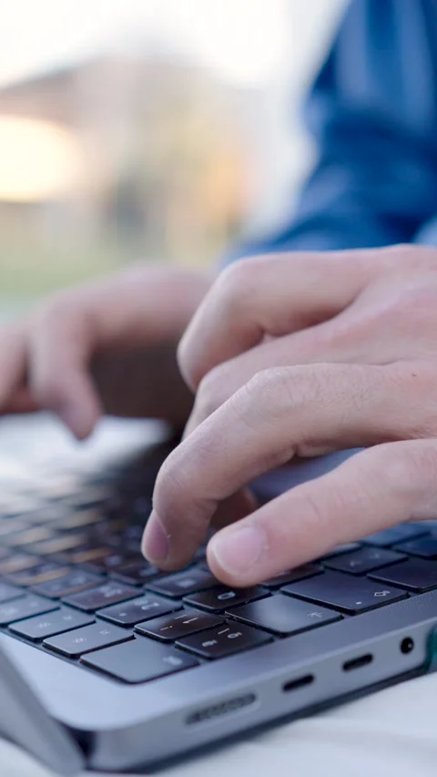 Programmer writing code outdoors on laptop keyboard. Vertical Stock Footage 304891564