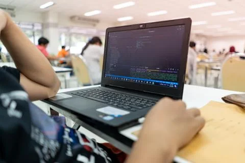A programmer is writing a program on a laptop outside the office. Concept of  Stock Photos