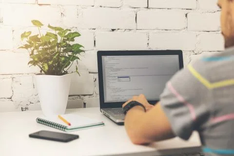 Programmer writing programming code on laptop in bright office Stockfoto's