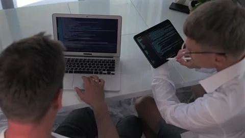 Programmers collaborate, optimizing code on laptop and tablet. Stock Footage 294298760