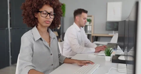 Programmers collaborating at computers in bright office, focused developers at Stock Footage 340997960