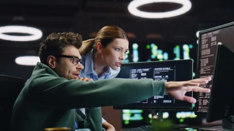 Programmers couple working together in dark room closeup. Analysts discussing Stock Footage 260259583