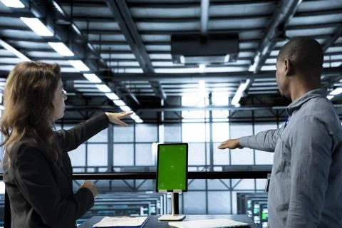 Programmers in data center using mockup laptop, inspecting server rigs Foto stock