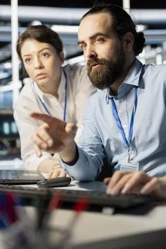 Programmers in data center workplace using computer, verifying firewall Foto stock