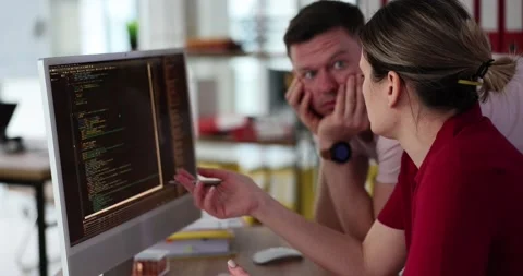 Programmers discuss code structure at computer monitor Stock Footage 239993741