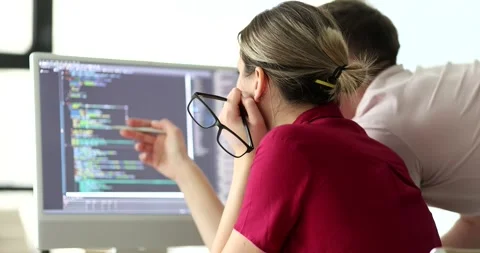 Programmers discuss code structure at monitor in office Video stock 279550244