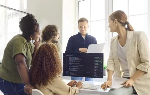 Programmers discuss code in team meeting at modern office with computer monitor Photos