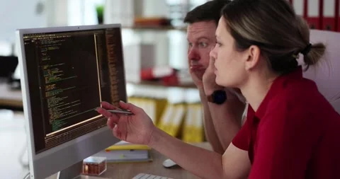 Programmers discuss error in code on computer monitor screen Stock Footage 241487141