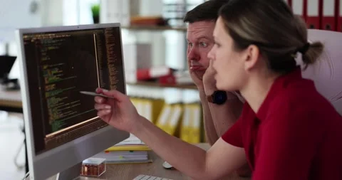 Programmers discuss error in code on computer monitor screen Stock Footage 275586755