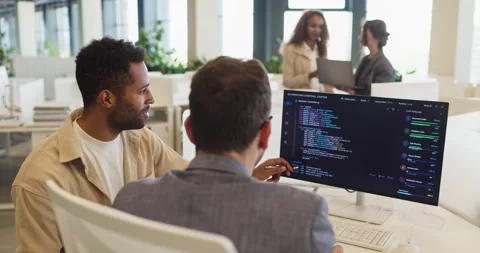 Programmers discussing code on desktop monitor in bright modern collaborative 스톡 동영상 337548381