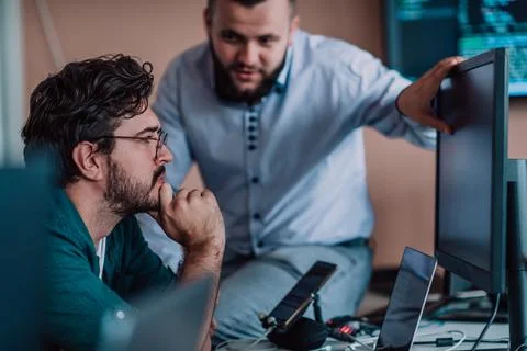 Programmers engrossed in deep collaboration, diligently working together to Stock Photos