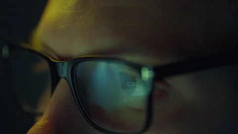 A programmer's eyes are locked in close-up on a bright computer monitor as h Stock Footage 255681060