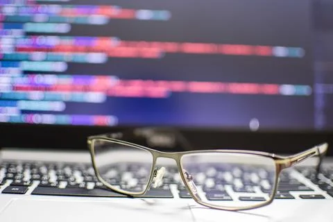 The programmer's glasses put on the keyboard laptop to relax after long cod.. Stock Photos