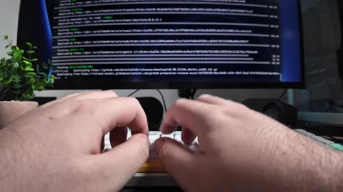 Programmer's hands actively typing on a sleek keyboard with lines of code d.. Stock Footage 320174387