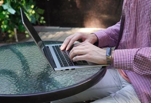 The programmer's hands work on the keyboard of a laptop standing on a glass Foto stock
