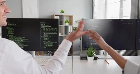 Programmers highfive to celebrate success while coding together on dual monitors 스톡 동영상 337928745