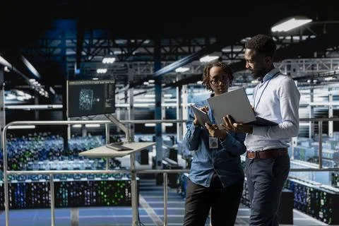 Programmers team in data center reviewing AI LLM visualizations on devices Foto stock