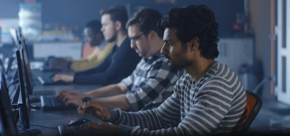 Programmers working and one turning to the camera Stock Photos