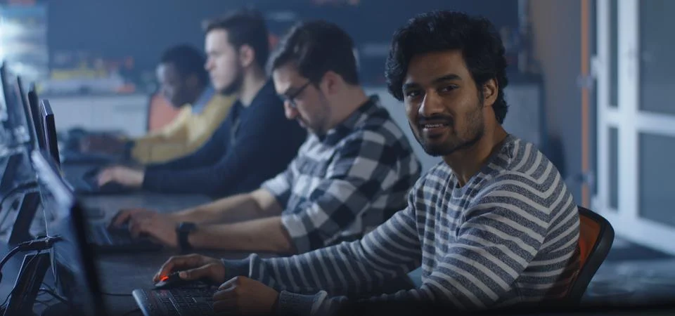 Programmers working and one turning to the camera Stock-Fotos