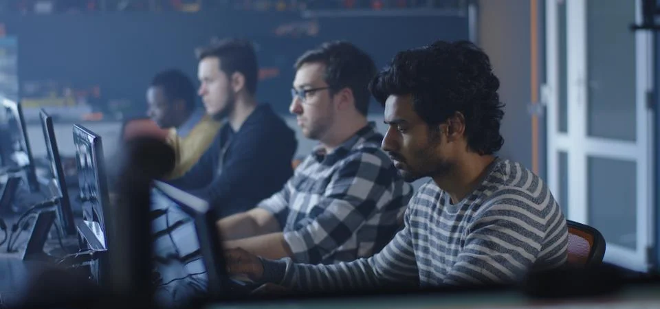 Programmers working and one turning to the camera Stock Photos
