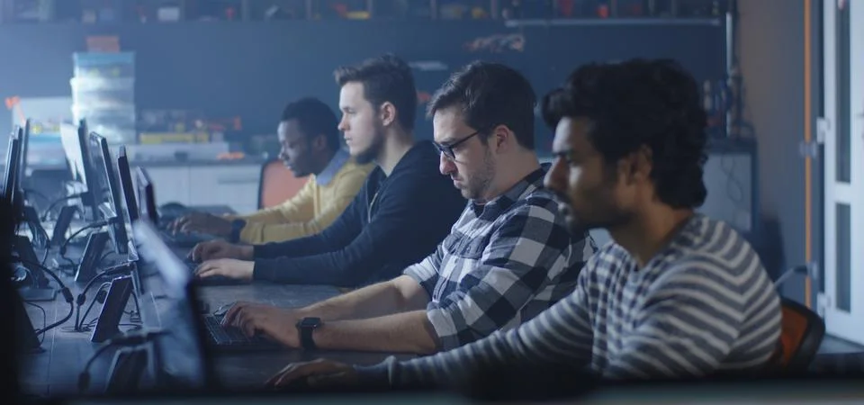 Programmers working and one turning to the camera Stock-Fotos