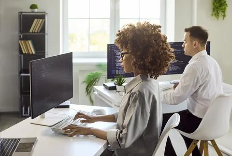 Programmers working on code in bright office, dual monitors and collaboration Stock-Fotos