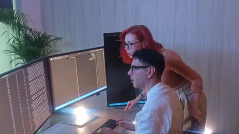 Programmers working at night analyzing code on monitors in a modern office. Stock Footage 333998977