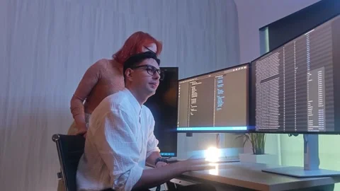 Programmers working at night analyzing code on monitors in a modern office. Stock Footage 333998994