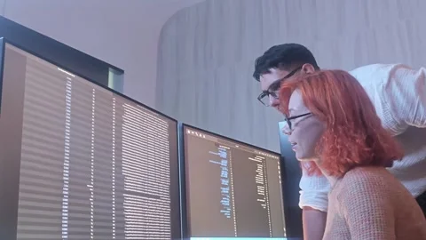 Programmers working at night analyzing code on monitors in a modern office. 스톡 동영상 333999026