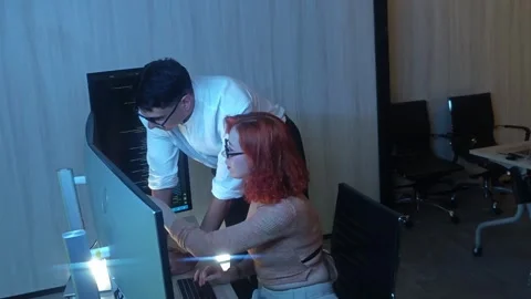 Programmers working at night analyzing code on monitors in a modern office. Stock Footage 333999029