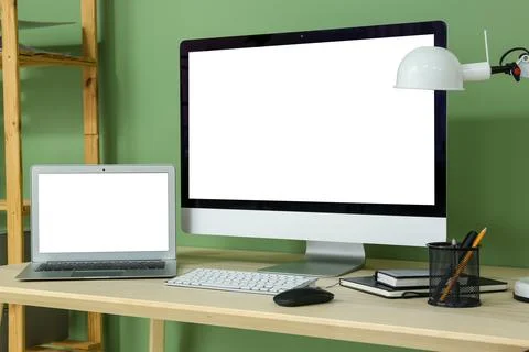 Programmer's workplace with blank laptop and computer near green wall in offi Stock Photos