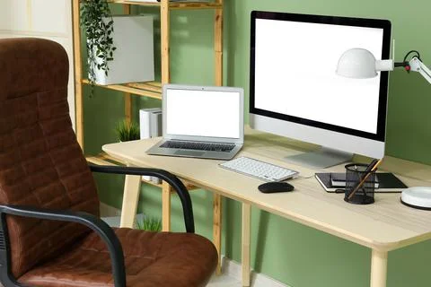 Programmer's workplace with blank laptop and computer near green wall in offi Stock-Fotos