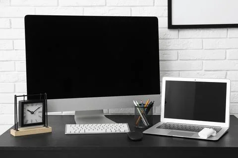 Programmer's workplace with blank laptop and computer near white brick wall i Stock-Fotos