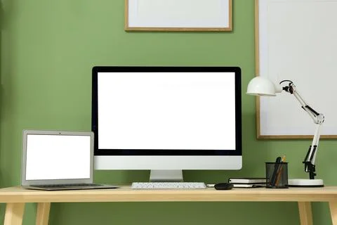 Programmer's workplace with blank laptop and computer near green wall in offi Stock Photos