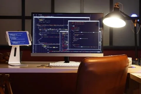 Programmer's workplace with computer and glowing lamp in dark office Stock Photos