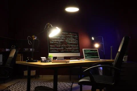 Programmers workplace with computer, laptop and glowing lamps in dark office 스톡 사진