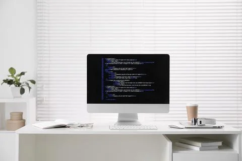 Programmer's workplace. Modern computer with unfinished code, coffee and su.. Stock-Fotos