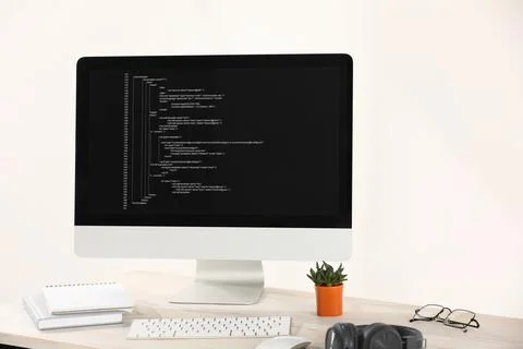 Programmer's workplace. Modern computer with unfinished code, headphones an.. Foto stock