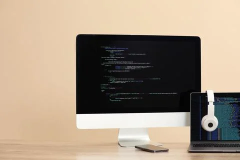 Programmer's workplace. Modern computer with unfinished code, laptop and ot.. Stock Photos