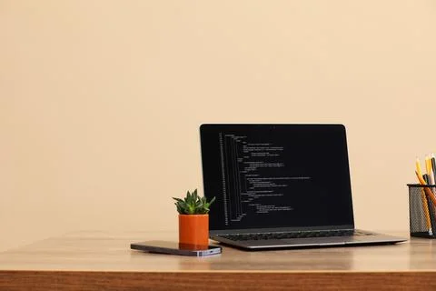 Programmer's workplace. Modern laptop with unfinished code on desk 写真素材
