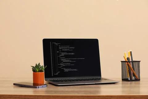 Programmer's workplace. Modern laptop with unfinished code on desk Stock Photos