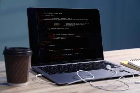 Programmer's workplace. Modern laptop with unfinished code, earphones and p.. 库存照片