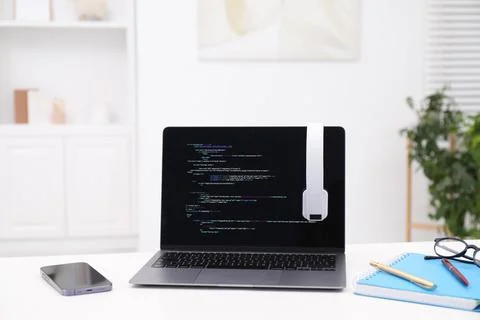 Programmer's workplace. Modern laptop with unfinished code, headphones and .. Stock Photos