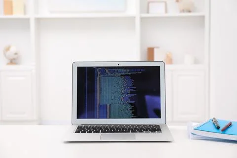 Programmer's workplace. Modern laptop with unfinished code, notebooks and p.. 库存照片