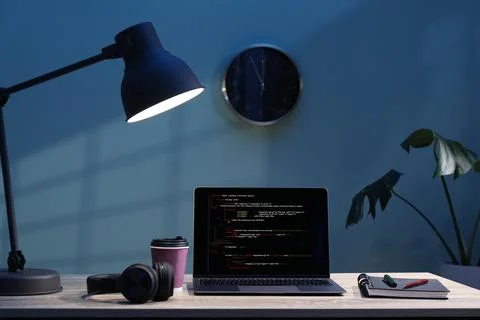 Programmer's workplace. Modern laptop with unfinished code, headphones and .. Stock Photos