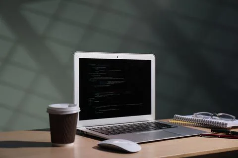 Programmer's workplace. Modern laptop with unfinished code and other suppli.. 写真素材