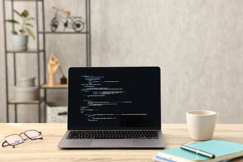Programmer's workplace. Modern laptop with unfinished code, glasses cup and.. Stock Photos