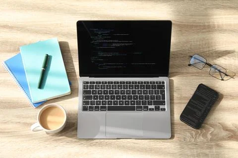 Programmer's workplace. Modern laptop with unfinished code, smartphone and .. 库存照片